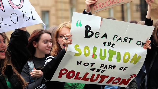 Students protesting for climate change and pollution. The poster says, Be a part of the solution not the part of the pollution. Great leaders never