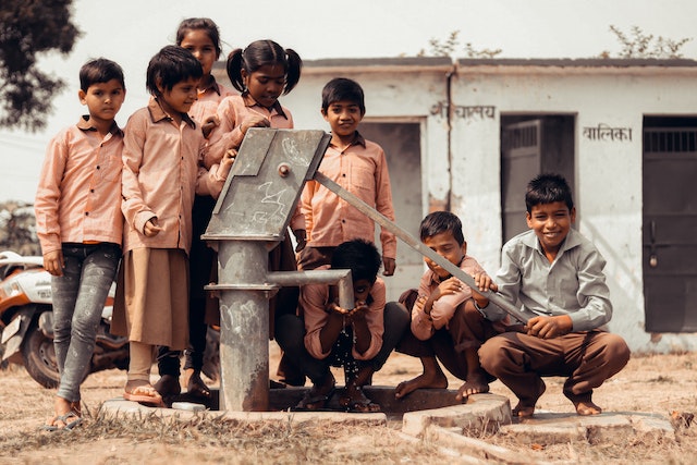 Happy School Kids drinking water from handpump. Education system in India needs a revamp, so that kids develop critical thinking and reasoning at early age.