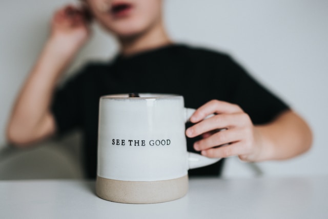 A boy holding a mug with caption "SEE THE GOOD" The intention is most important while giving feedback and criticism.