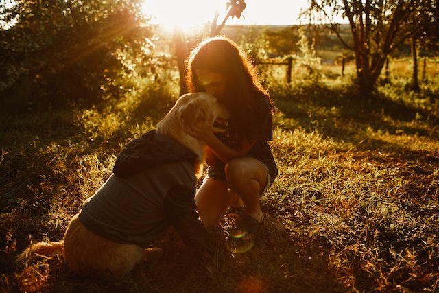 A woman kissing a dog in the field. 

Unlocking Empathy - 10 Heartfelt Ways to Practice It in Daily Life A blog post by Gaurav Sinha, discussing the importance of empathy.