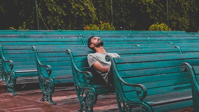 A man sitting and closing eyes on teal bench, 
Boredom Is Good: The Sweetness of Doing Nothing! a blogpost by Gaurav Sinha